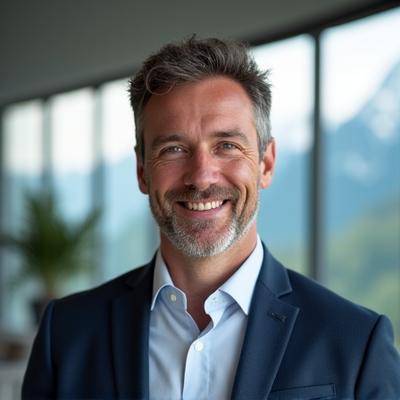 Porträt von Thomas Meier, Geschäftsführer von Alpenglüh Grillkultur mit einem vertrauenswürdigen Lächeln vor einer dezenten alpinen Kulisse.